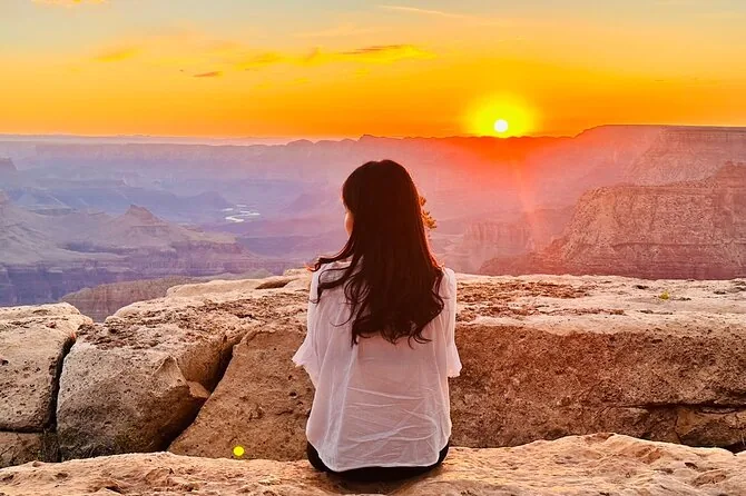 A traveler watching sunrise from the Grand Canyon rim